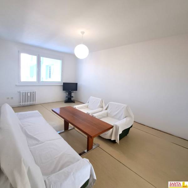 Wohnzimmer mit Tisch und Sofa in einer 4-Zimmer-Wohnung, Boden mit Holzdekor.