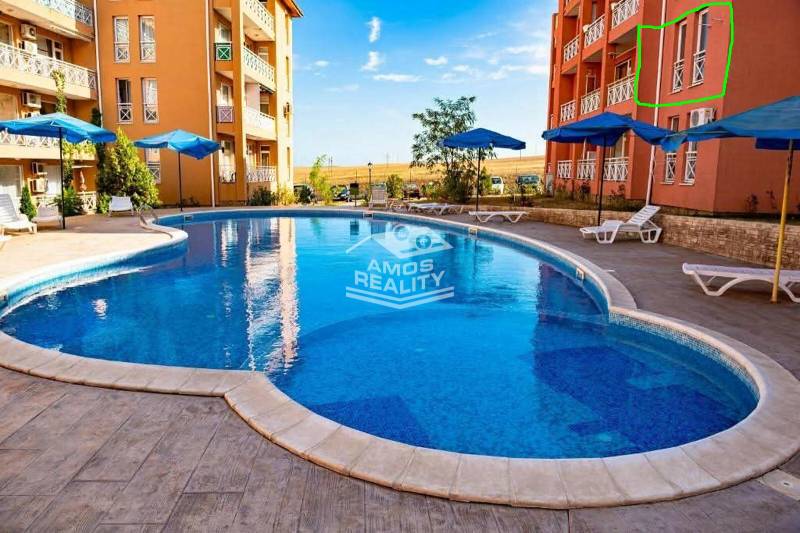 Ferienwohnung in Burgas mit Pool, Liegestühlen und Sonnenschirmen auf der gepflasterten Terrasse.