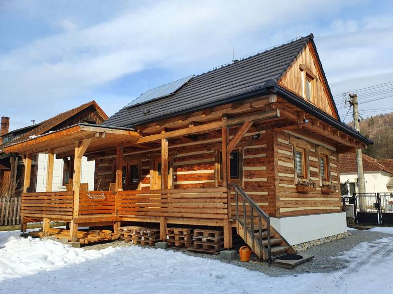 Holzhütte in der Hviezdoslav-Straße in Tisovec, bedeckt mit Schnee und Sonnenkollektoren.