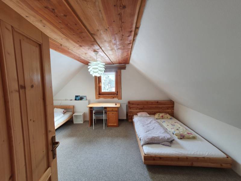 Ein Zimmer in einer Hütte mit einer Holzdecke, zwei Betten und einem Tisch.