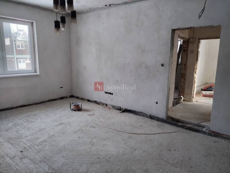 Innenraum eines im Bau befindlichen Einfamilienhauses mit nackten Wänden und Betonboden.