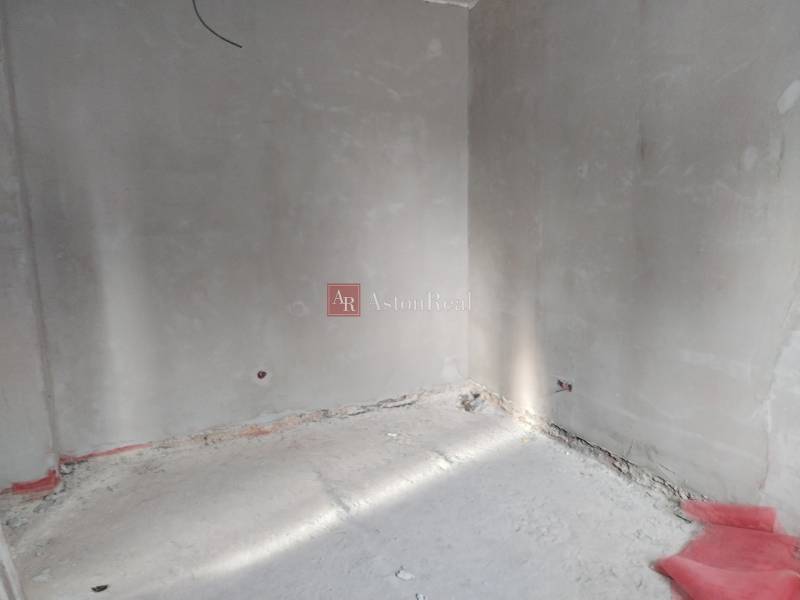 Ein leerer Innenraum mit unverputzten Wänden und Betonboden in einem Einfamilienhaus.