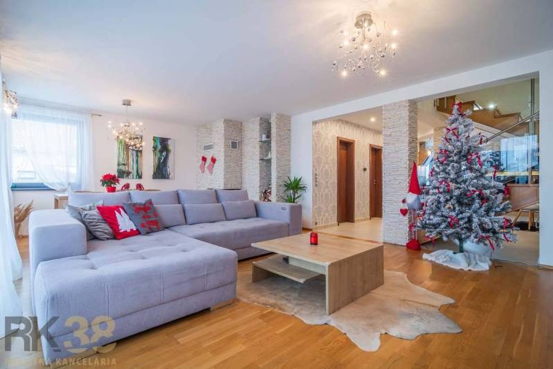 Wohnzimmer eines Einfamilienhauses mit Sofa, Weihnachtsbaum und Holzboden.