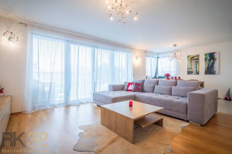 Wohnzimmer in einem Einfamilienhaus mit geräumigem Sofa und Boden in Holzoptik.
