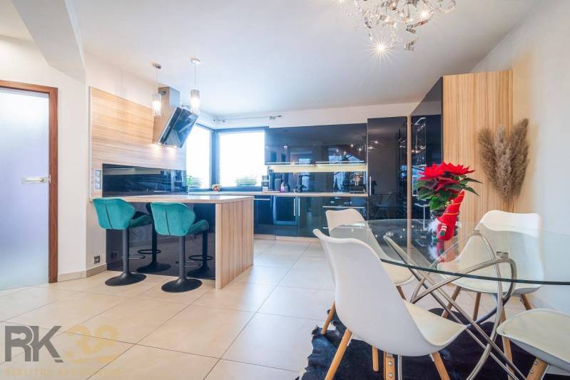 Eine helle Küche mit Esstisch und Barhockern in einem Einfamilienhaus.