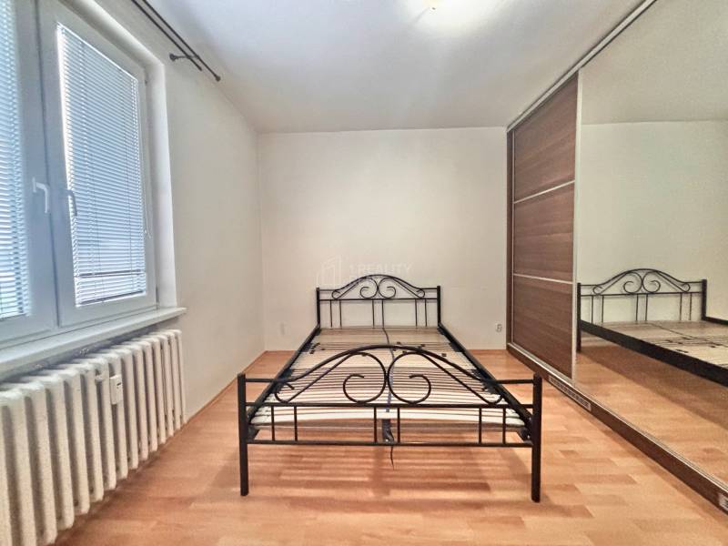 Schlafzimmer mit einem Metallbett, einem Einbauschrank und einem Boden mit Holzdekor in einer 3-Zimmer-Wohnung.