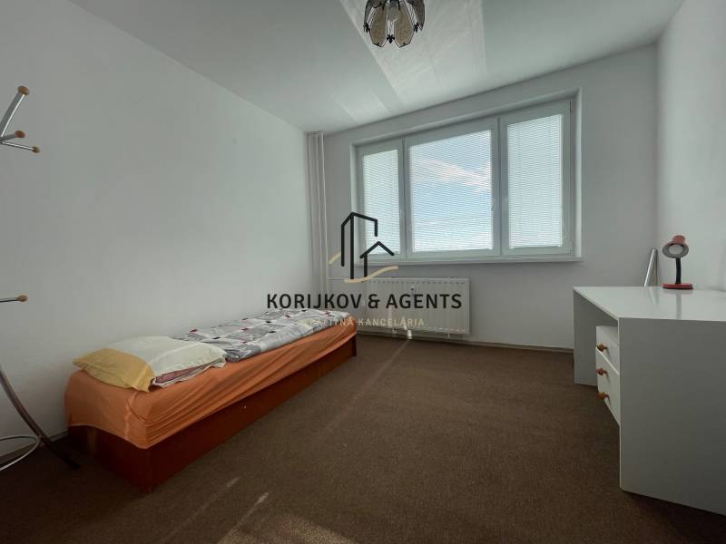 Einfaches Schlafzimmer mit Bett, Schreibtisch und Teppichboden in einer 3-Zimmer-Wohnung.