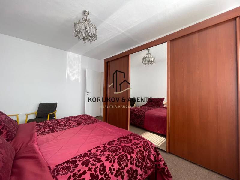 Schlafzimmer mit großem Schrank, Kronleuchter und Bett in einer 3-Zimmer-Wohnung.