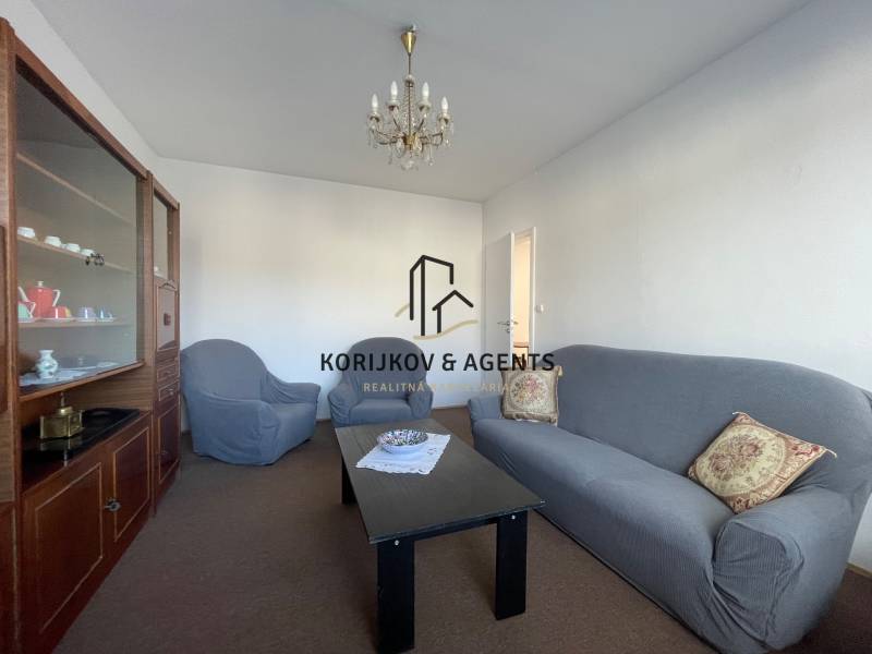 Wohnzimmer in einer 3-Zimmer-Wohnung mit einem bequemen Sofa, Sesseln und einer Vitrine.