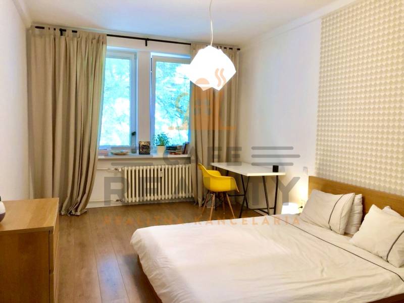 Schlafzimmer in einer 2-Zimmer-Wohnung mit Holzboden und Schreibtisch.