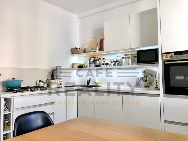 Küche in einer 2-Zimmer-Wohnung mit weißen Schränken und eingebauten Geräten.