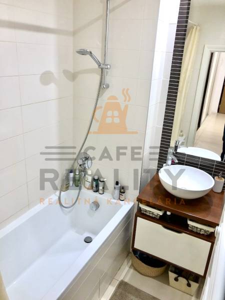 Badezimmer in einer 2-Zimmer-Wohnung mit Badewanne, Dusche und stilvollem Waschtischunterschrank.