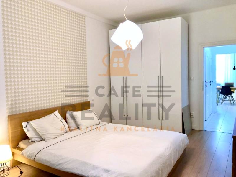 Schlafzimmer in einer 2-Zimmer-Wohnung mit weißem Schrank und Boden in Holzoptik.