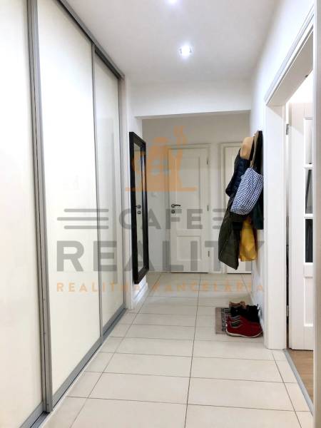 Der Flur mit Fliesen und einem Schrank in einer 2-Zimmer-Wohnung, mit Kleiderhaken.