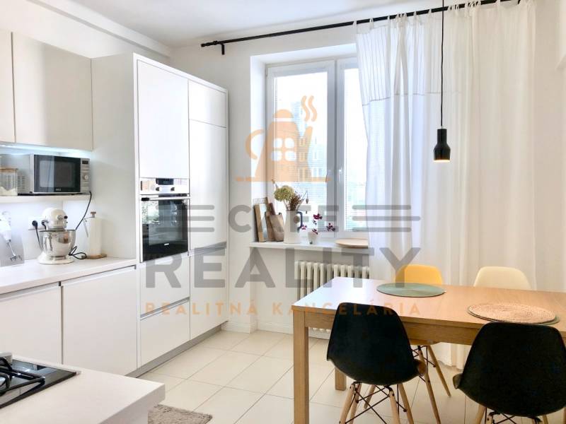 Küche in einer 2-Zimmer-Wohnung mit weißen Schränken und einem Esstisch mit Stühlen.