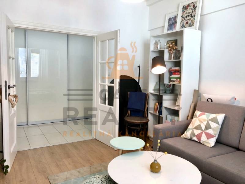 Wohnzimmer mit Holzboden, Sofa und Bücherregal in einer Zweizimmerwohnung.