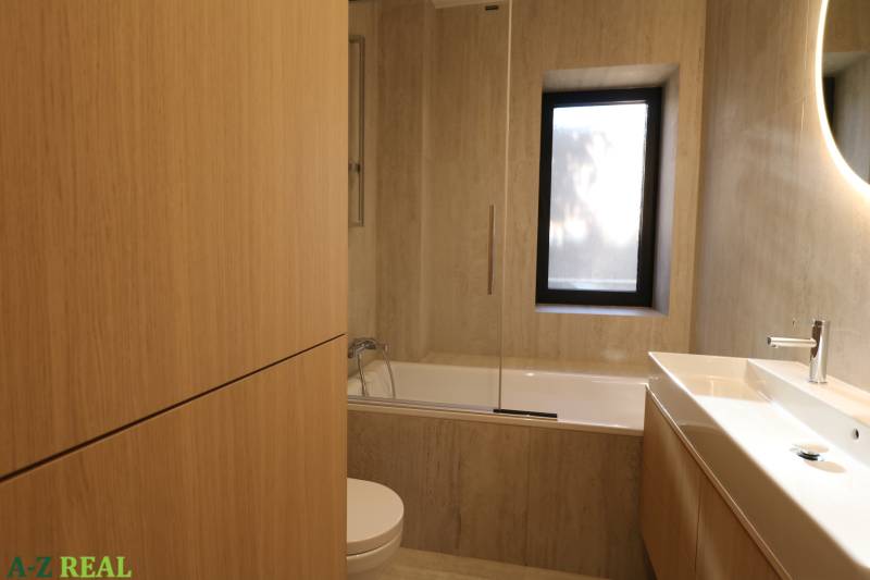 Badezimmer mit Badewanne und Waschbecken in einer 4-Zimmer-Wohnung mit Holzelementen.