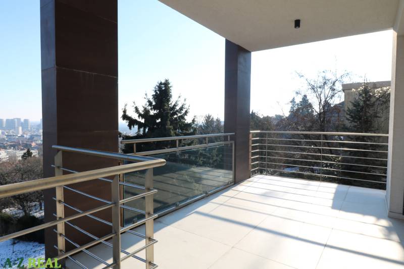 Ein Balkon mit Geländer und Blick auf die Stadt von einer 4-Zimmer-Wohnung in Bratislava.