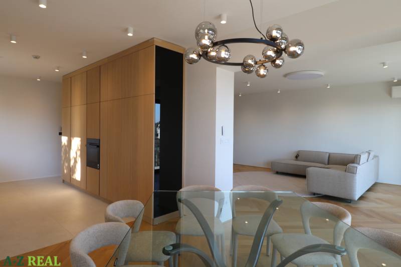 Wohnzimmer mit Esstisch, Sofa und Leuchte in einer 4-Zimmer-Wohnung, Boden mit Holzdekor.