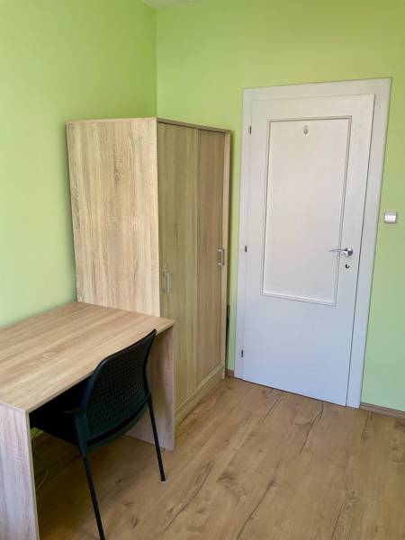Grünes Zimmer mit Holzmöbeln und Holzboden in einer 3-Zimmer-Wohnung.