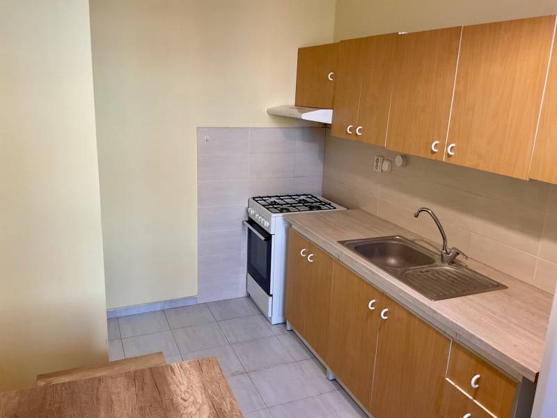 Küche in einer 3-Zimmer-Wohnung mit Gasherd und Holzschränken.