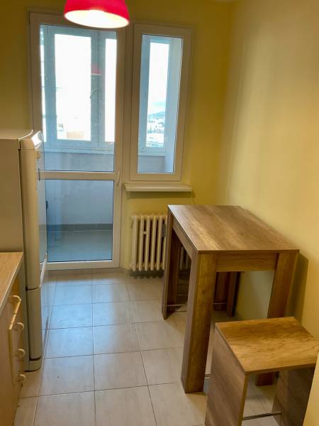 Küche in einer 3-Zimmer-Wohnung mit großen Fenstern, Bartisch und Stühlen.