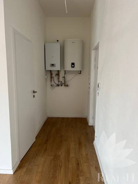Der Flur in der 2-Zimmer-Wohnung mit einem Boden in Holzoptik und einem Boiler an der Wand.