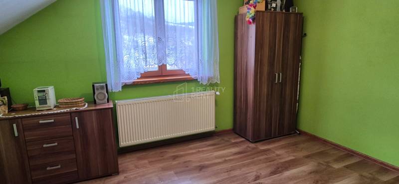 Ein Zimmer in einem Einfamilienhaus mit einem Boden in Holzoptik, grünen Wänden und Möbeln.