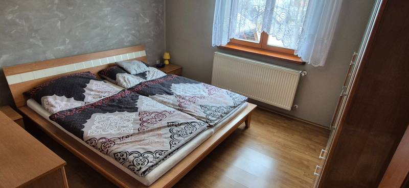 Schlafzimmer im Einfamilienhaus mit Bett, Schrank und Boden in Holzoptik.