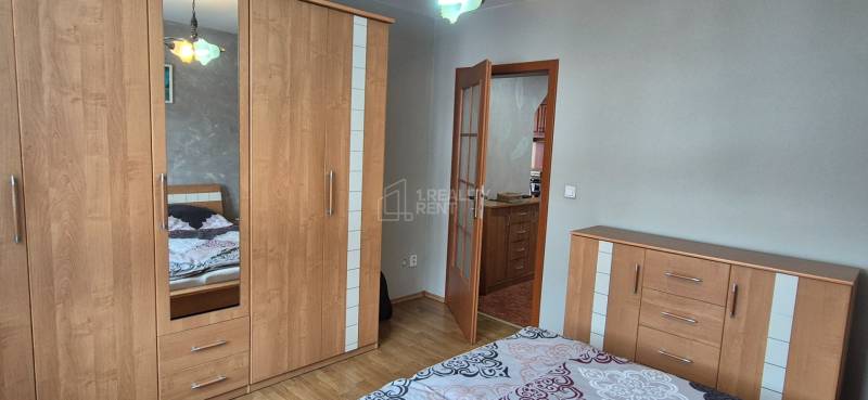Schlafzimmer im Einfamilienhaus mit Schrank, Holzboden und Zugang zur Küche.