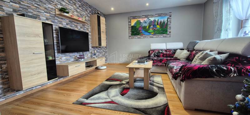 Wohnzimmer in einem Einfamilienhaus mit Holzboden, Stein an der Wand und einem bequemen Sofa.