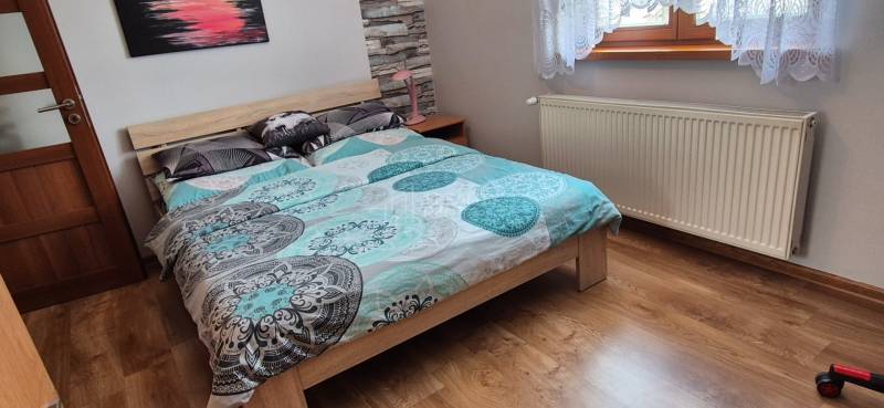 Schlafzimmer im Einfamilienhaus mit Bett, Heizkörper und Boden in Holzoptik.