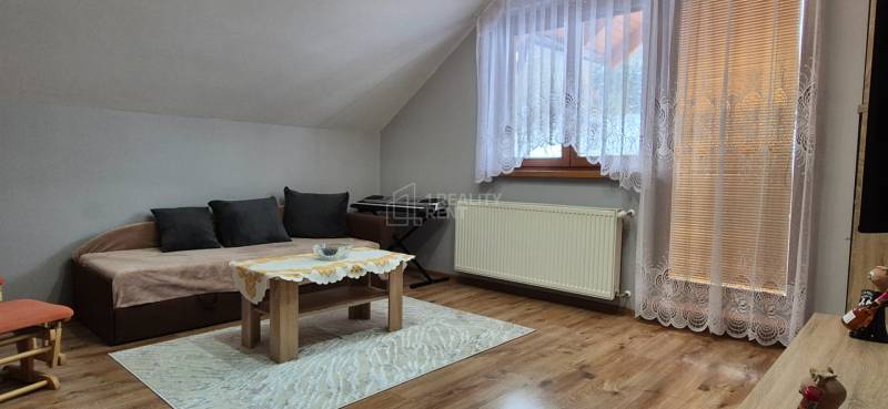 Wohnzimmer in einem Einfamilienhaus mit Sofa, Tisch, Teppich und Holzboden.