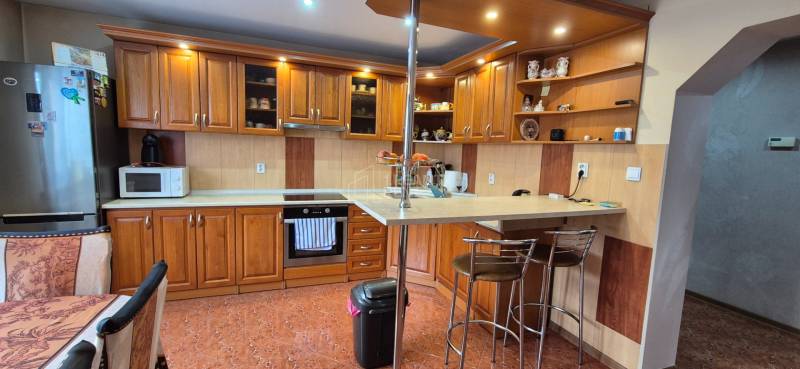 Küche in einem Einfamilienhaus mit Holzdekor, ausgestattet mit Geräten und einer Bar.