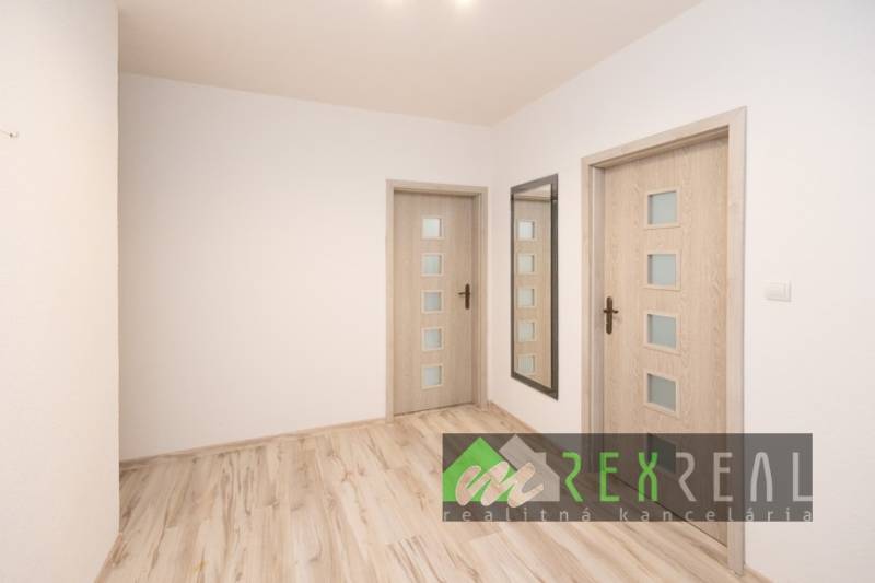 Flur in einer 3-Zimmer-Wohnung mit Holzboden und Spiegel.