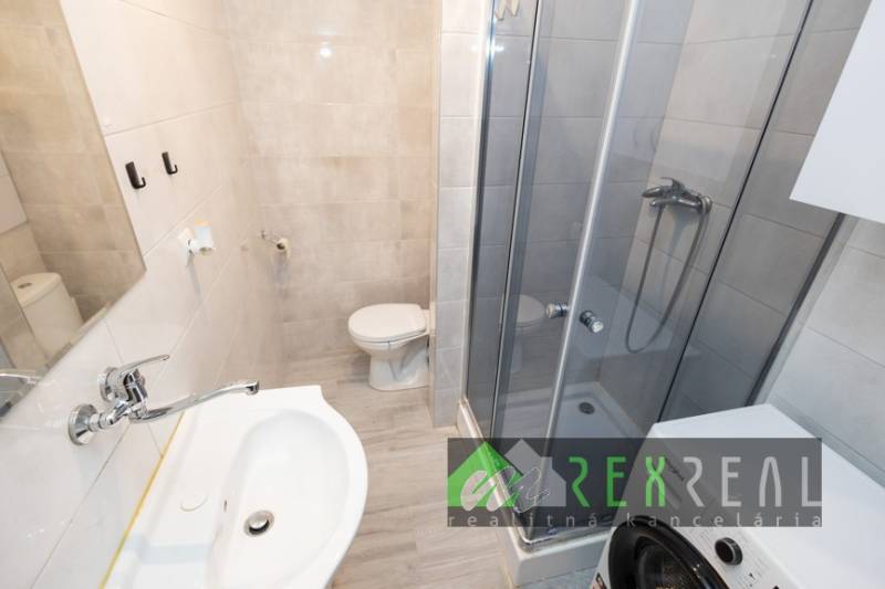 Badezimmer in einer 3-Zimmer-Wohnung mit Waschbecken, Duschkabine und Waschmaschine.