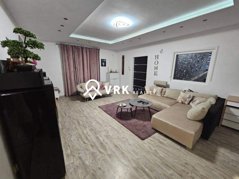 Wohnzimmer in einem Einfamilienhaus mit Holzboden und großem Sofa.