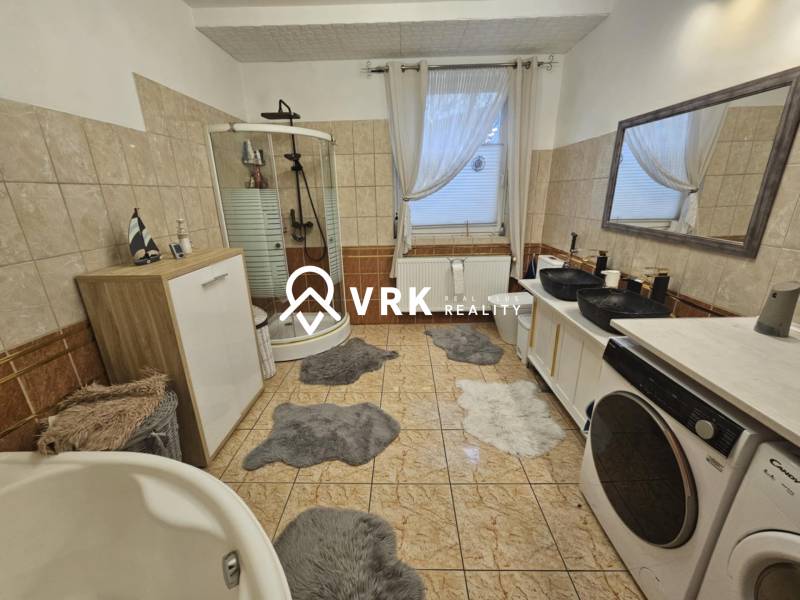 Badezimmer in einem Einfamilienhaus mit Badewanne, Dusche und Waschmaschine.