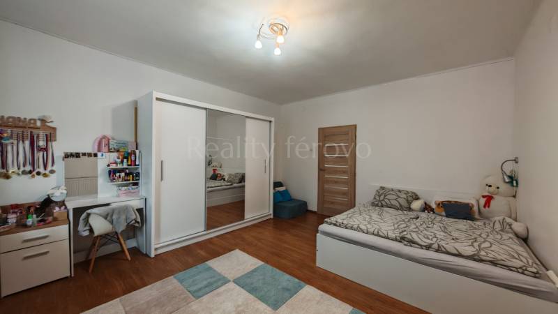 Kinderzimmer mit Bett, Schrank, Schreibtisch und Holzboden in einem Einfamilienhaus.