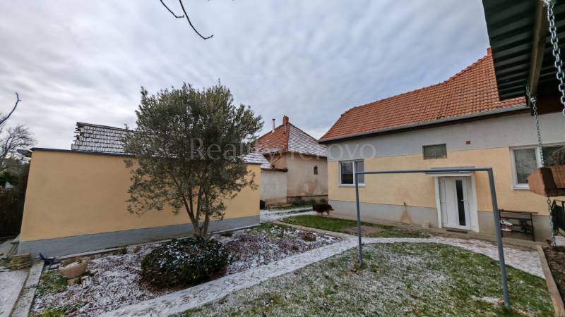 Ein verschneiter Garten mit einem Einfamilienhaus in Trnovec nad Váhom, umgeben von Bäumen und Rasen.