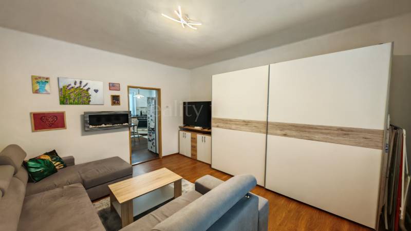 Wohnzimmer in einem Einfamilienhaus mit Holzboden, Sofa und Bildern an der Wand.