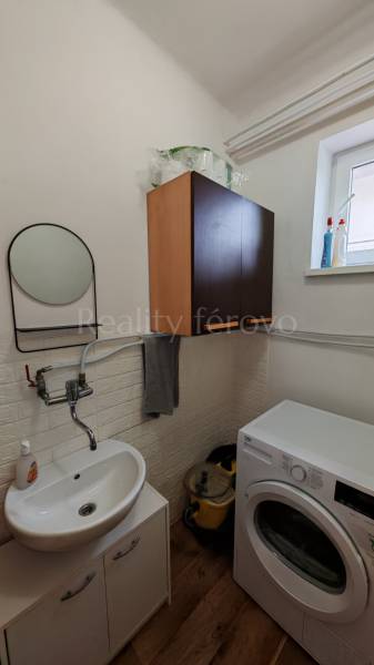 Badezimmer mit Waschbecken, Waschmaschine und Schrank, Boden mit Holzdekor.