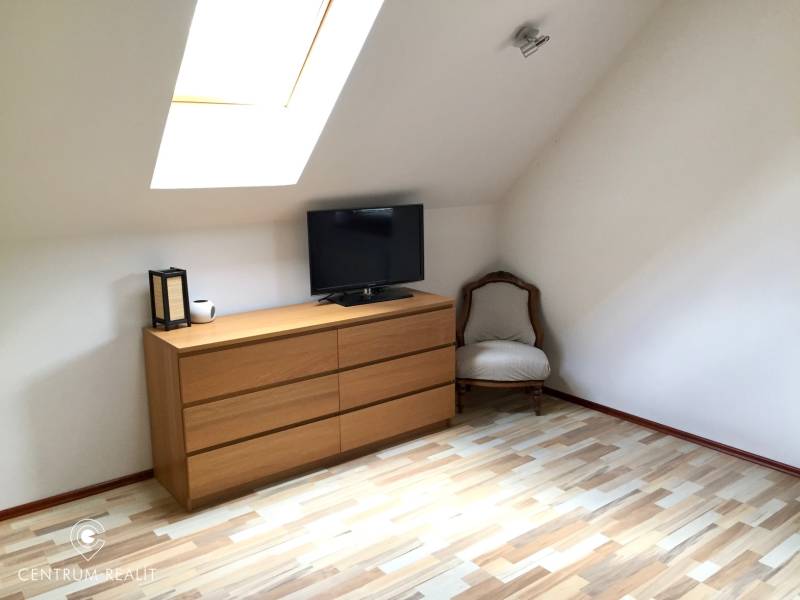 Innenraum eines Einfamilienhauses mit Kommode, Sessel und Boden in Holzoptik.