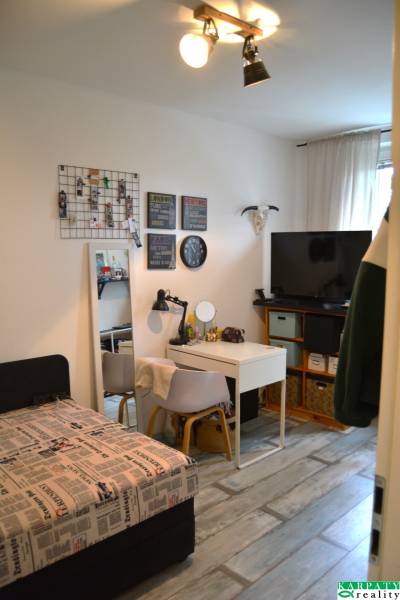 Ein Zimmer mit Bett, Schreibtisch und Dekorationen in einer 3-Zimmer-Wohnung, Boden mit Holzdekor.