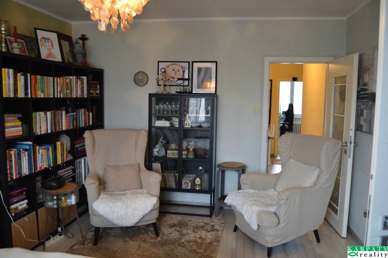 Wohnzimmer in einer 3-Zimmer-Wohnung mit Bücherregalen und einem Boden in Holzoptik.