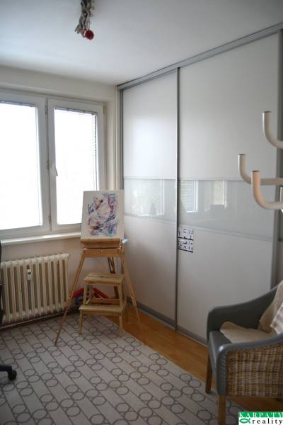 Einfaches Interieur einer 3-Zimmer-Wohnung mit einem Sessel, einem Tischchen und einem Schrank.