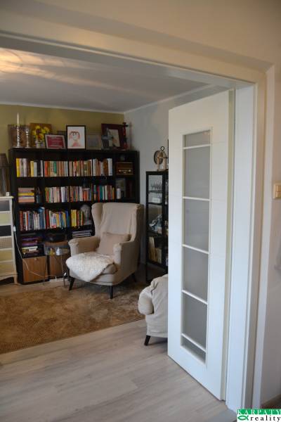 Leseecke mit einem bequemen Sessel und Büchern in einer 3-Zimmer-Wohnung mit Holzboden.