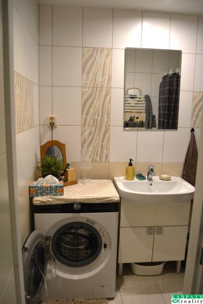 Badezimmer in einer 3-Zimmer-Wohnung mit Spiegel, Waschbecken und Waschmaschine.