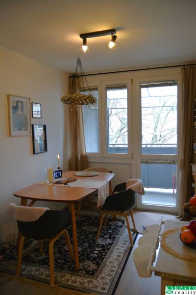 Essbereich in einer 3-Zimmer-Wohnung mit Teppichdekor und verglasten Balkontüren.