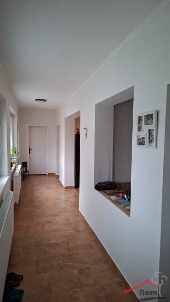 Der Flur eines Einfamilienhauses mit Fliesenboden und weißen Wänden, mit einer offenen Tür auf der rechten Seite.